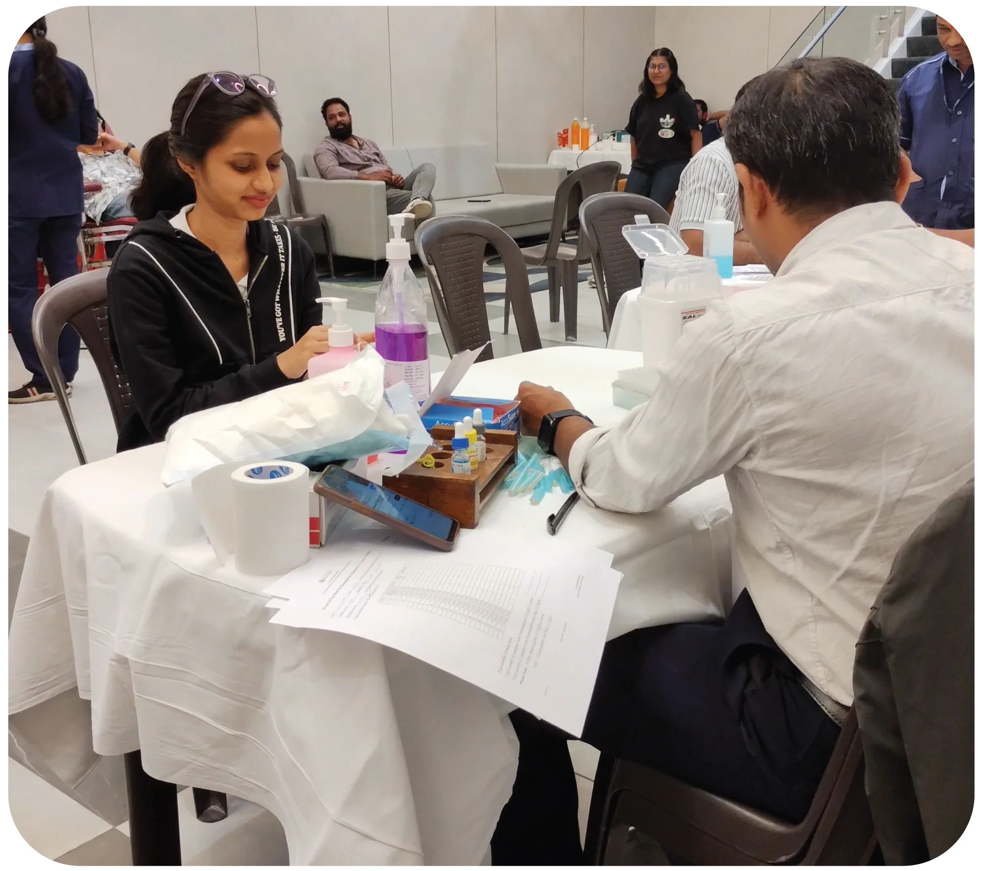 Nurse assisting donor during blood donation with equipment setup